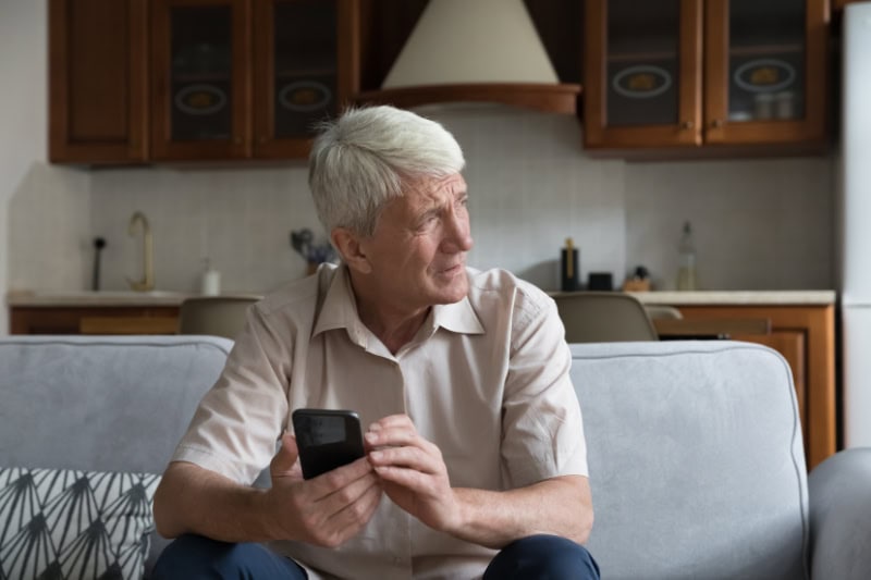 What’s That Smell Coming From My Furnace? Senior man sitting on his couch, looking out a window seemingly concerned.