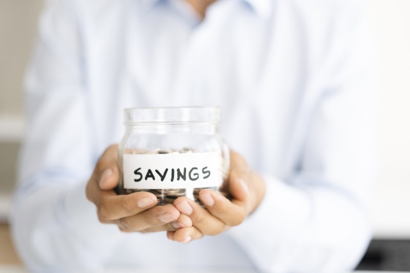 Why Buying a Heat Pump Instead of a Furnace Makes Sense. Phot of a person holding a jar of coins labeled "Savings".